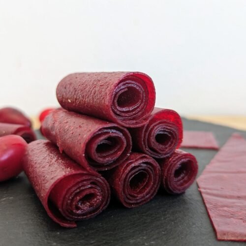 Homemade Cornelian cherry fruit leather rolls with fresh cherries.