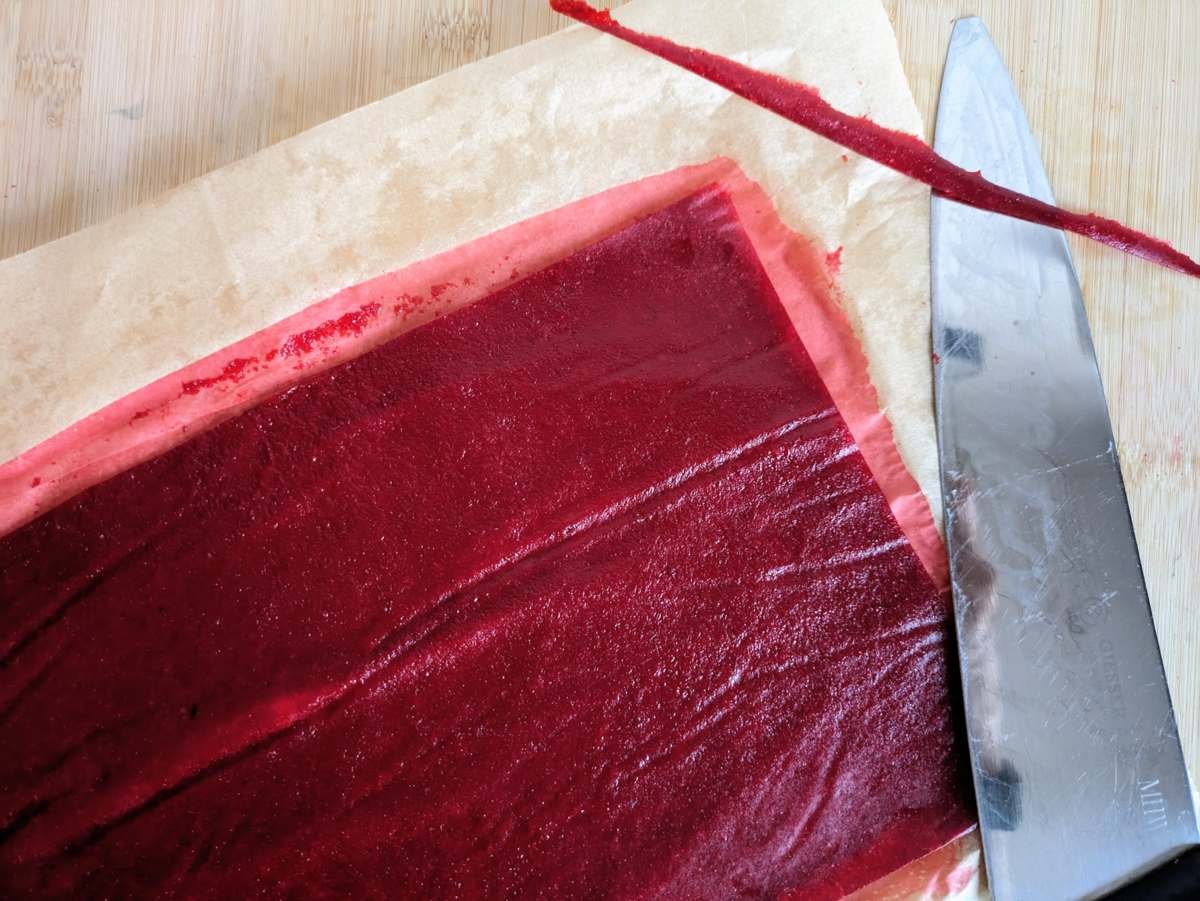 Dried Cornelian cherry fruit leather being trimmed and cut into strips.