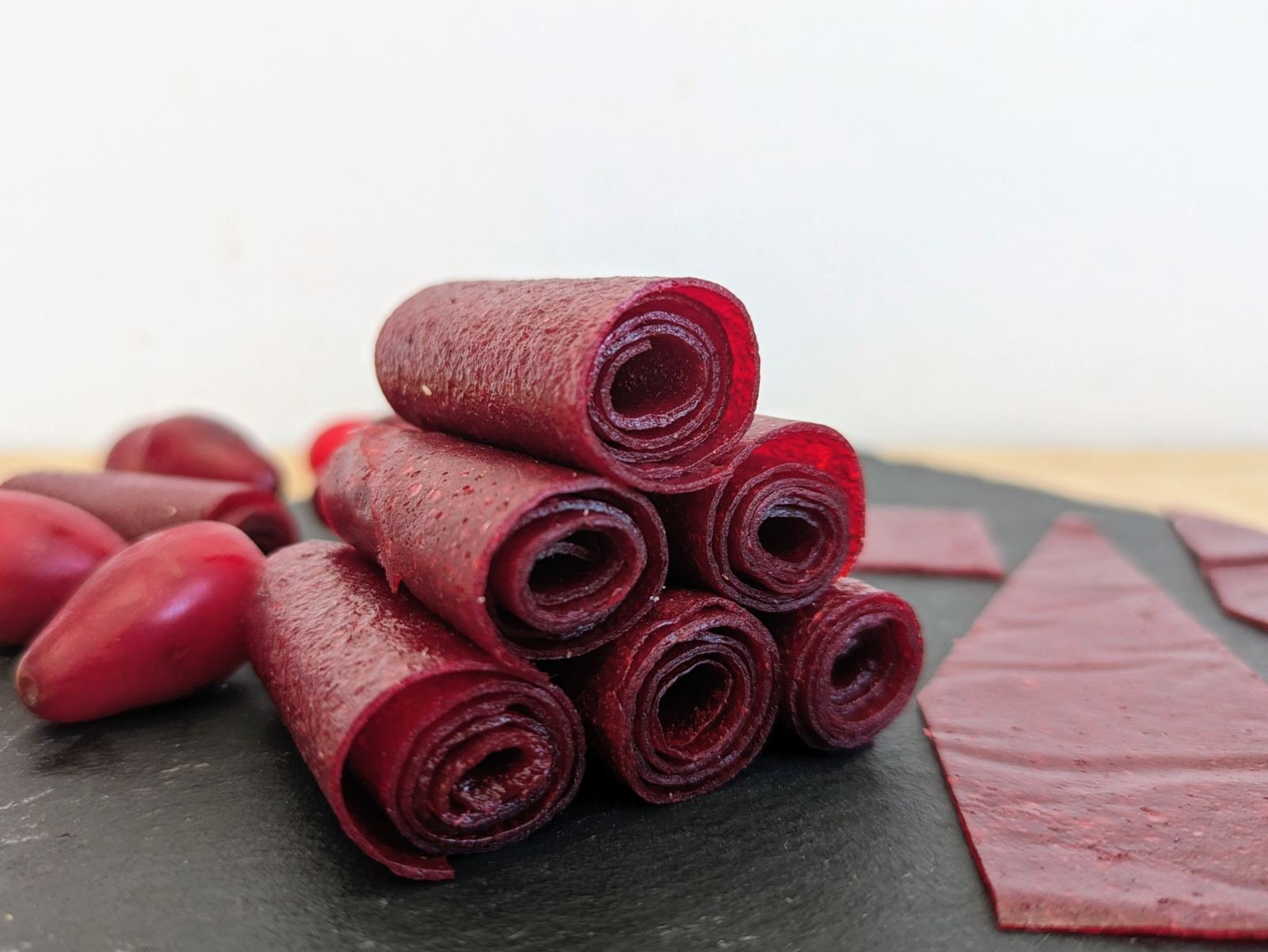 Homemade Cornelian cherry fruit leather rolls with fresh cherries.