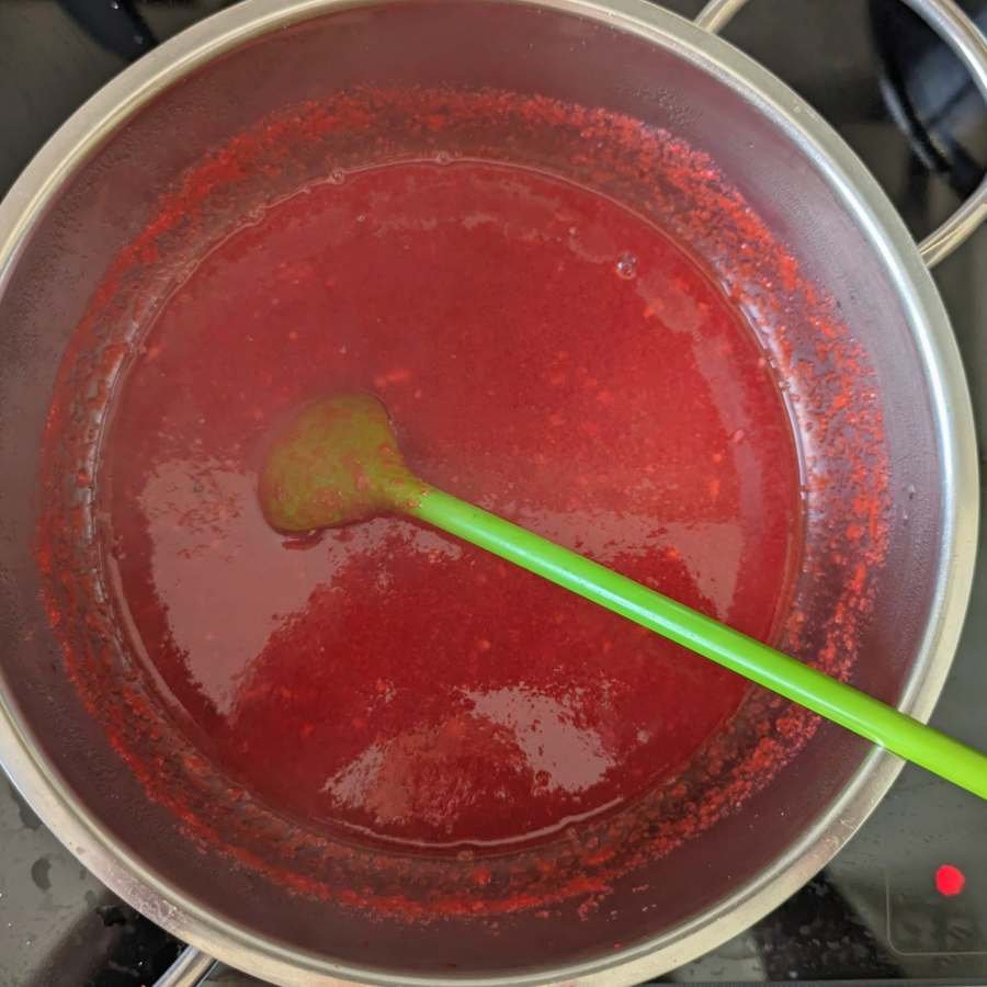 Cornelian cherry hot sauce simmering in a saucepan before blending and straining.
