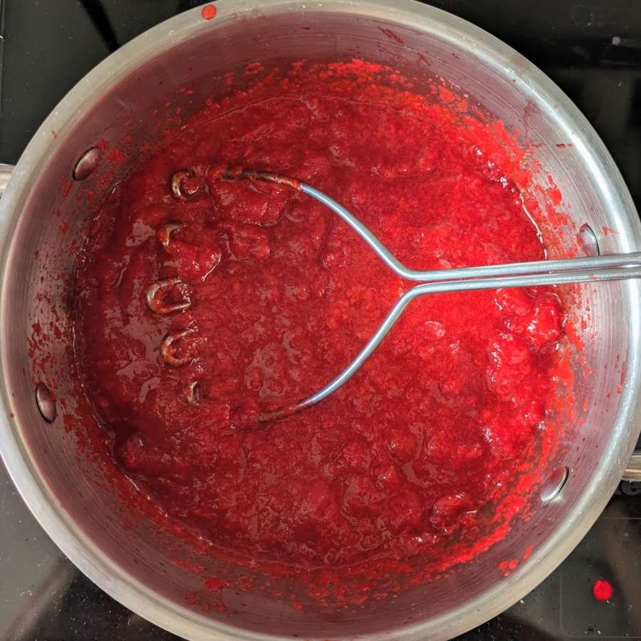Cornelian cherries being mashed as they soften and break down into pulp.