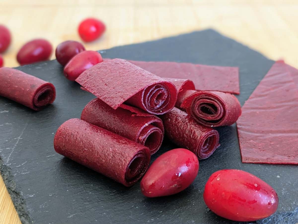 Homemade Cornelian cherry fruit leather rolls with fresh Cornelian cherries.