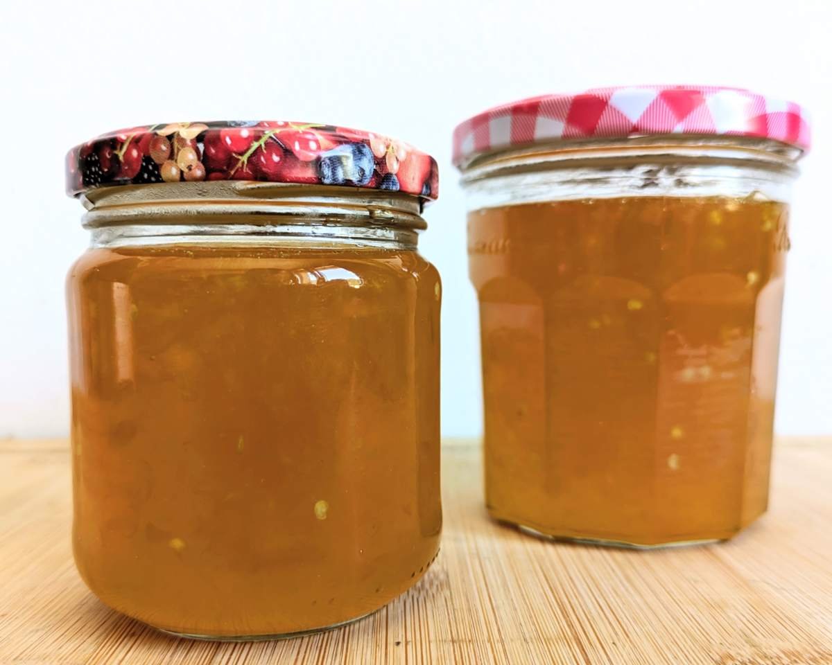 Two sealed jars of amber-gold Lemon Drop chilli jam on a wooden board.