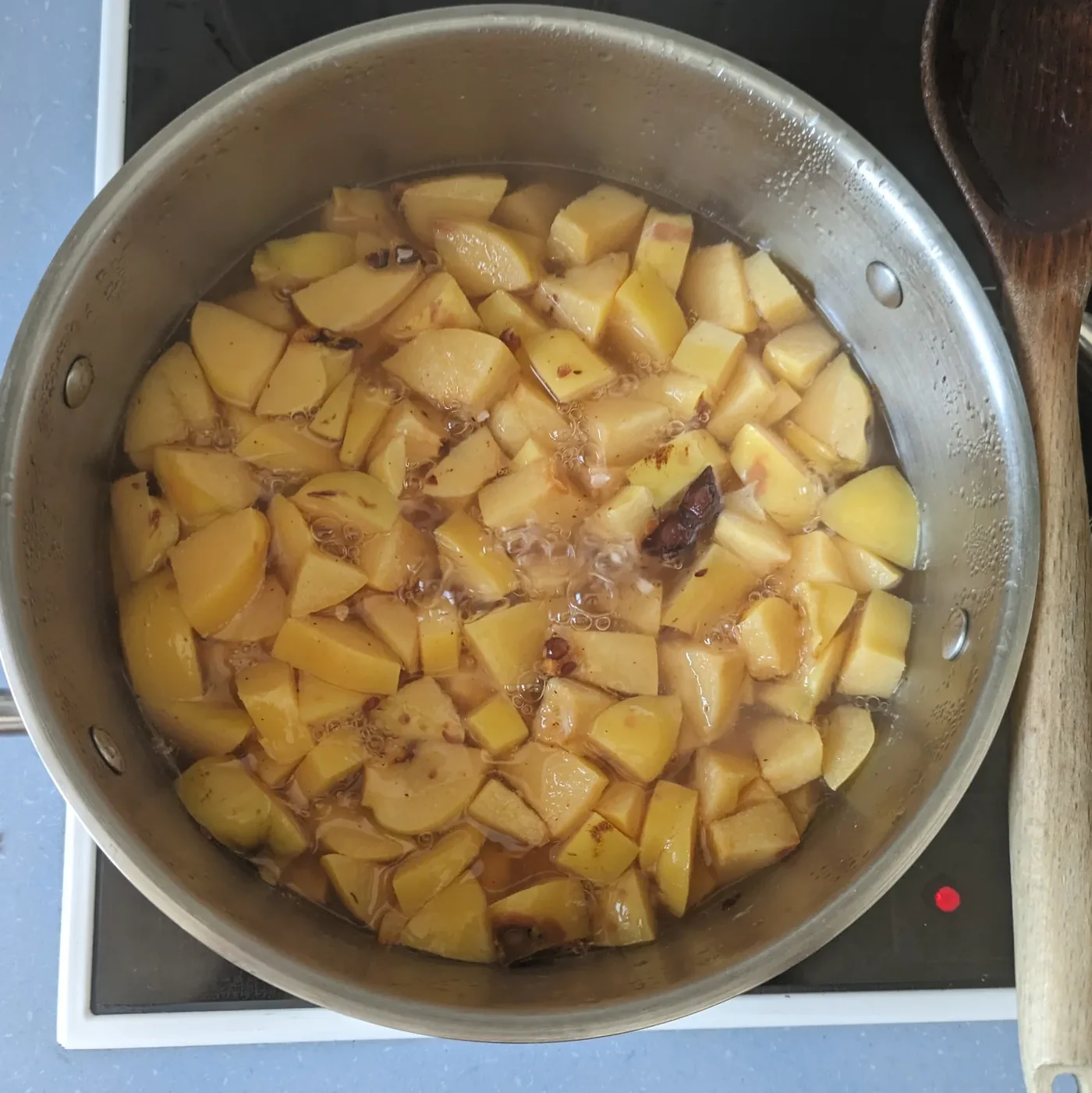 Soft cooked quince pieces in a saucepan before straining.