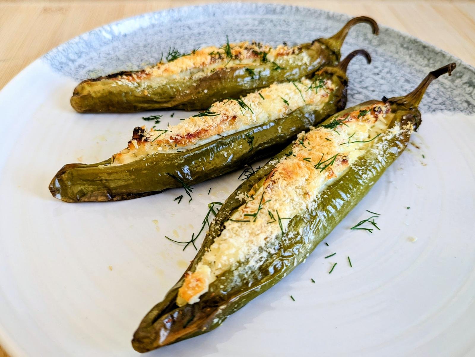 Stuffed Anaheim peppers with feta, golden breadcrumbs and chopped dill on a plate.