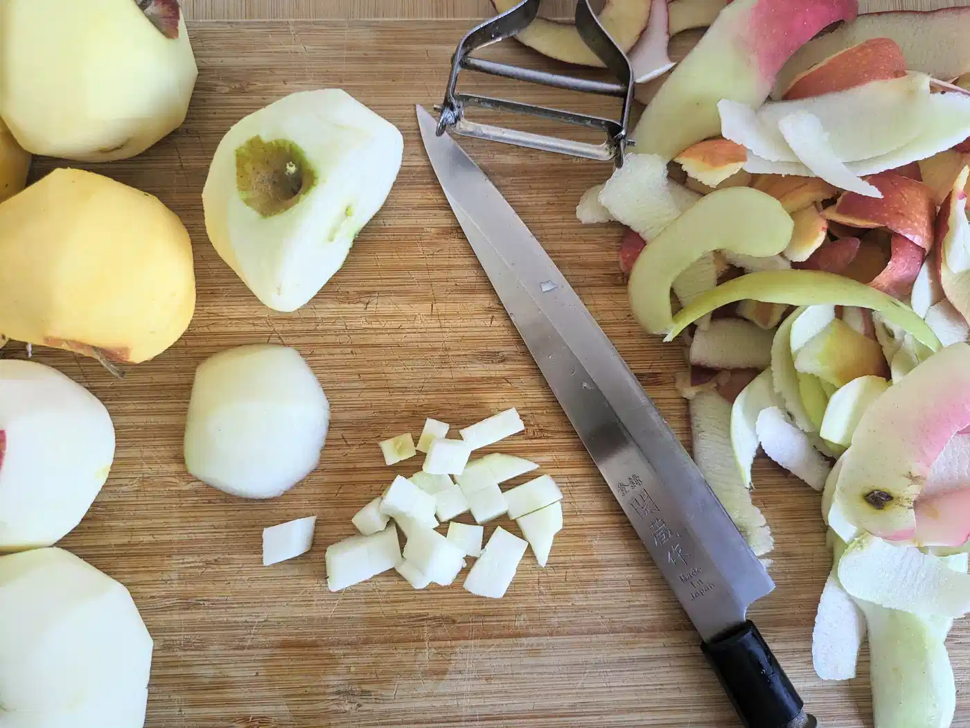 Apples being peeled and chopped on a wooden board