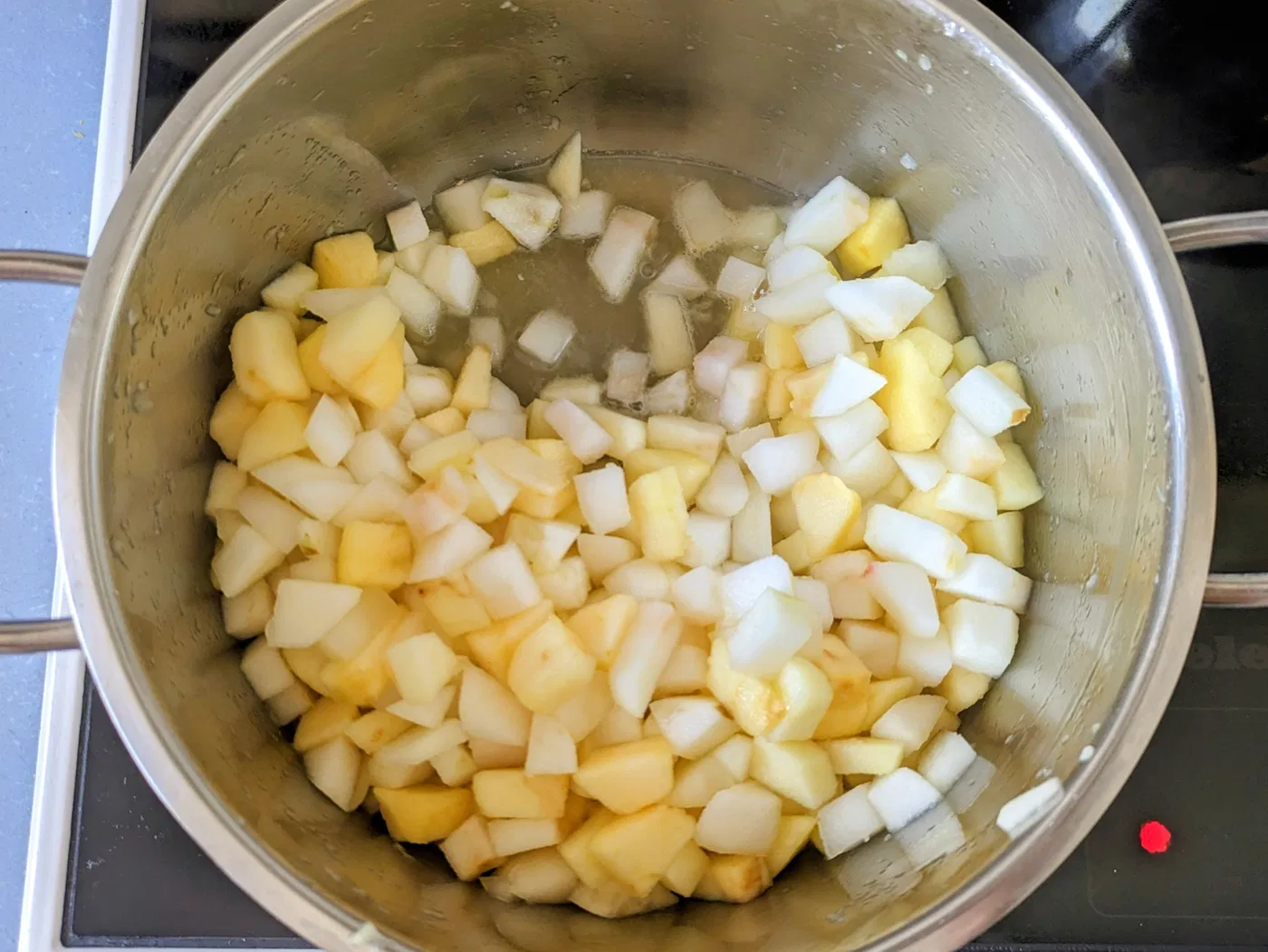 Peeled and diced apples in a saucepan showing cooking liquid
